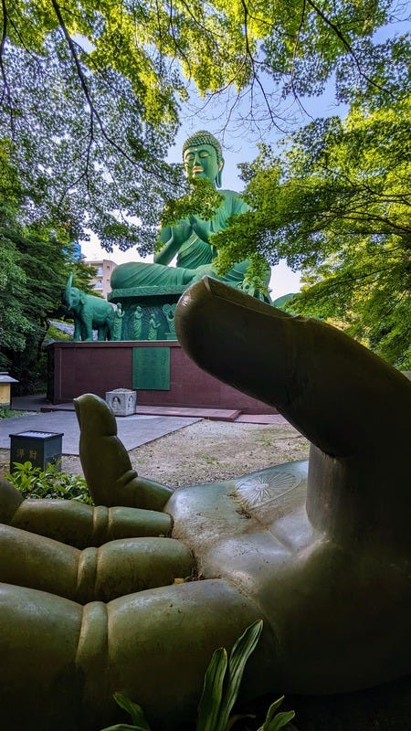 The giant Buddha sculpture from a distance with a sculpture of a giant hand in the foreground