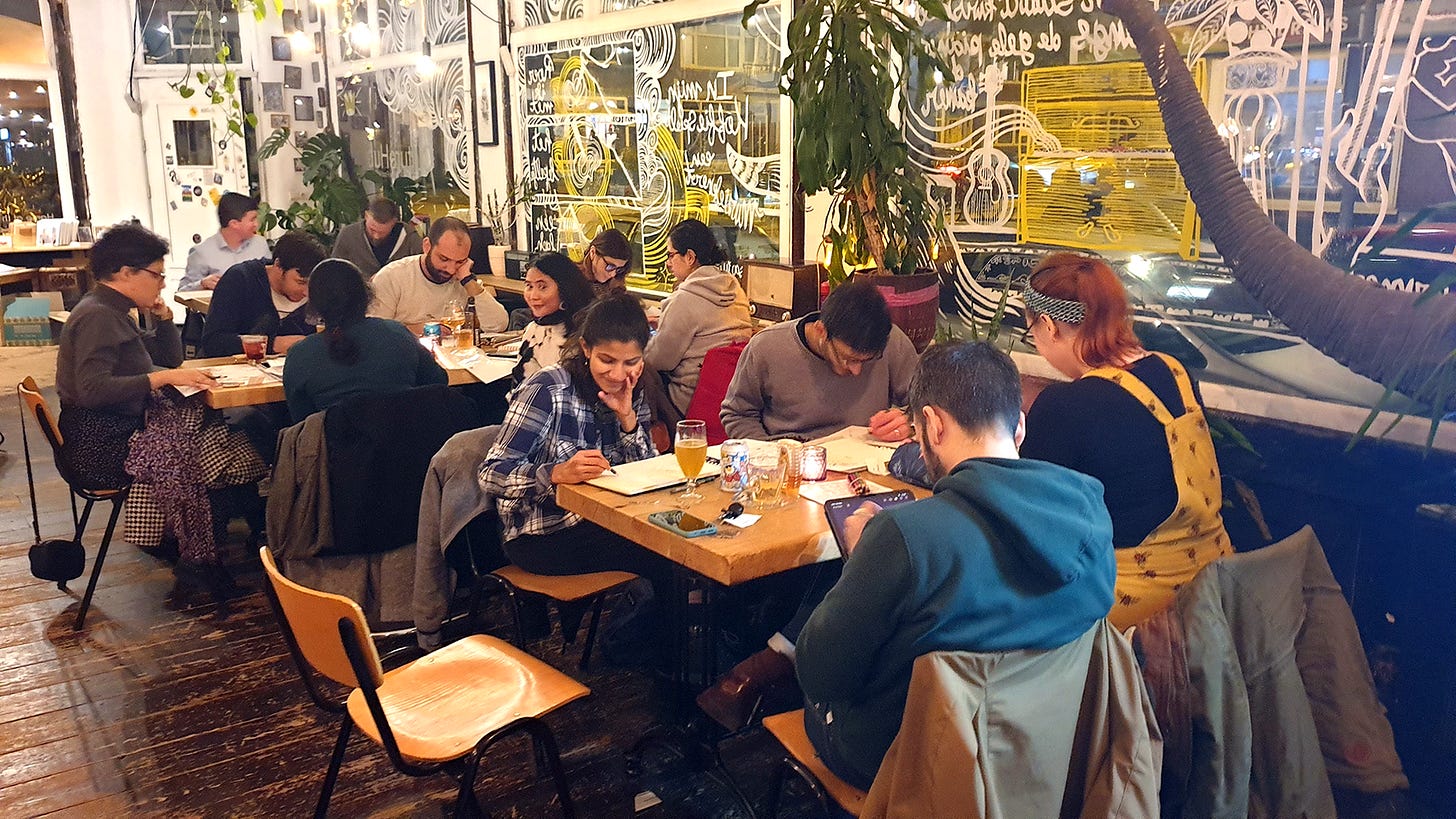 A café filled with people, happily drawing with each other. 