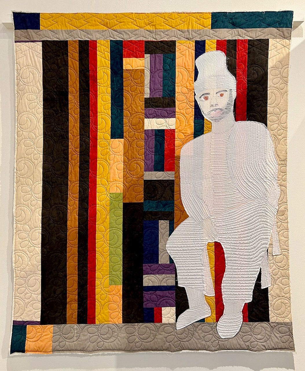 A quilt with a person in the back

Description automatically generated