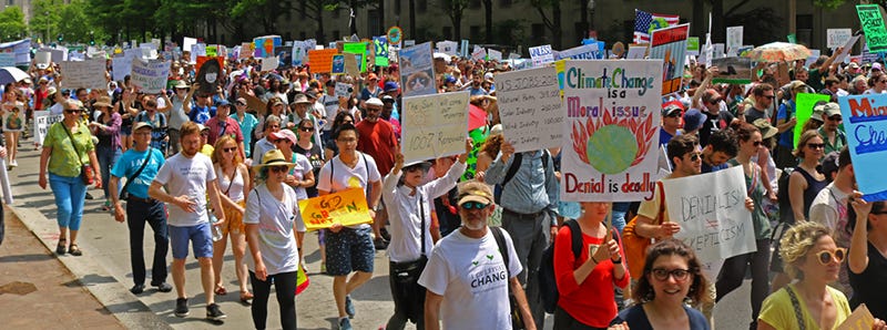 A climate protest with people walking and holding signs