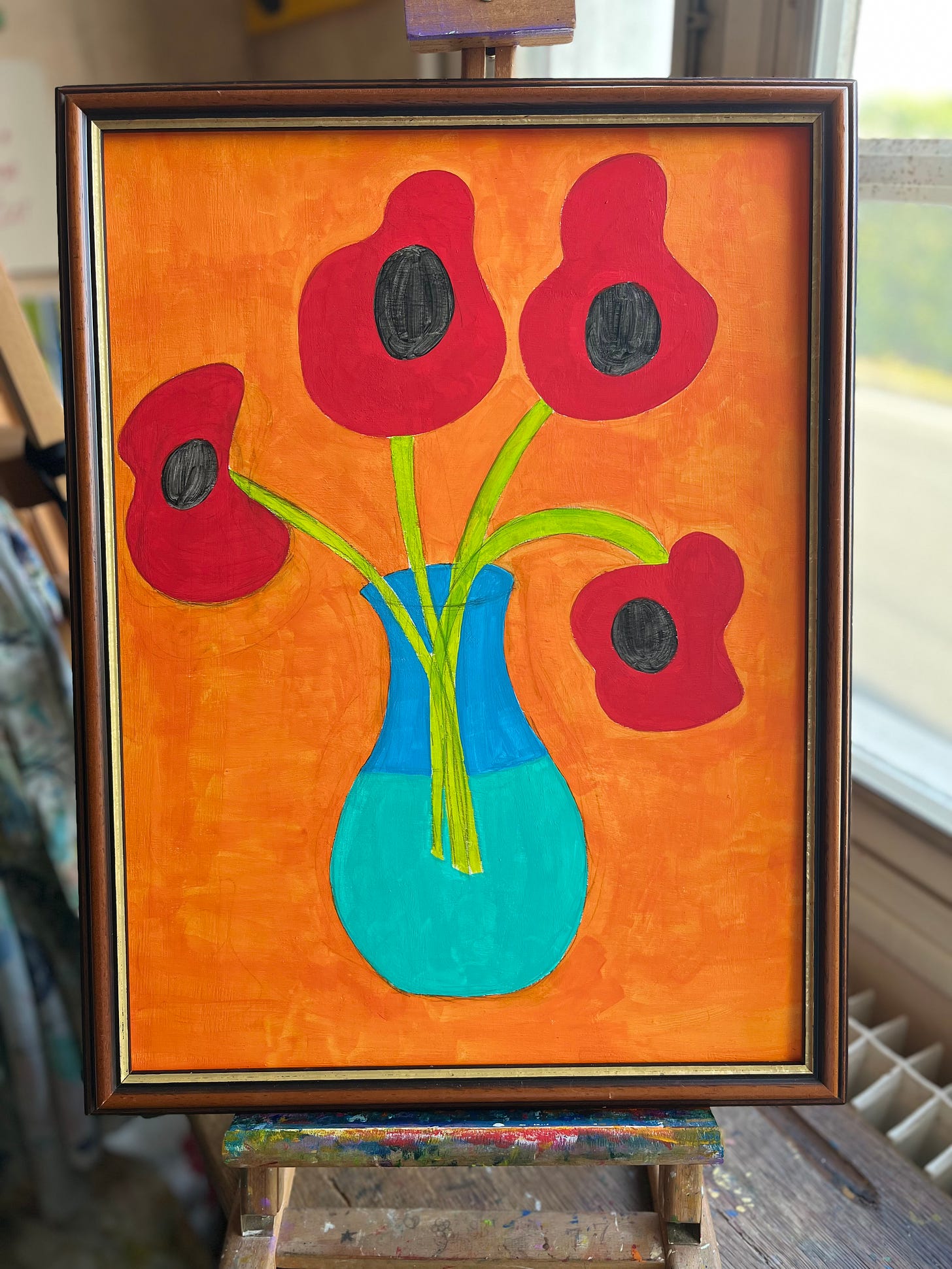 An acrylic painting of four red poppies in a vase on an orange background in a thrifted frame
