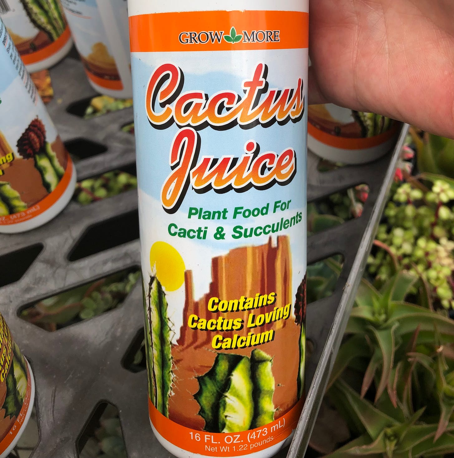 A plastic bottle of plant food called cactus juice with the image of a cactus and a desert mesa behind it. 