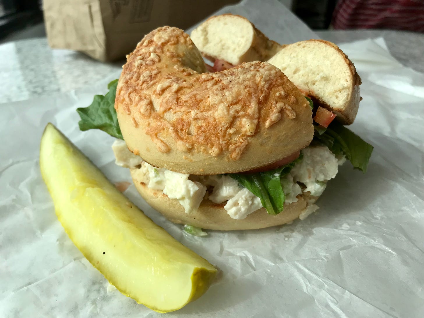 Chicken salad sandwich on Asiago bagel at Bagel Jay’s with pickle spear