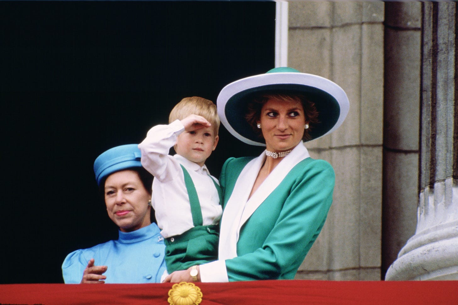 Princess Diana wearing green and white coat and holding Prince Harry