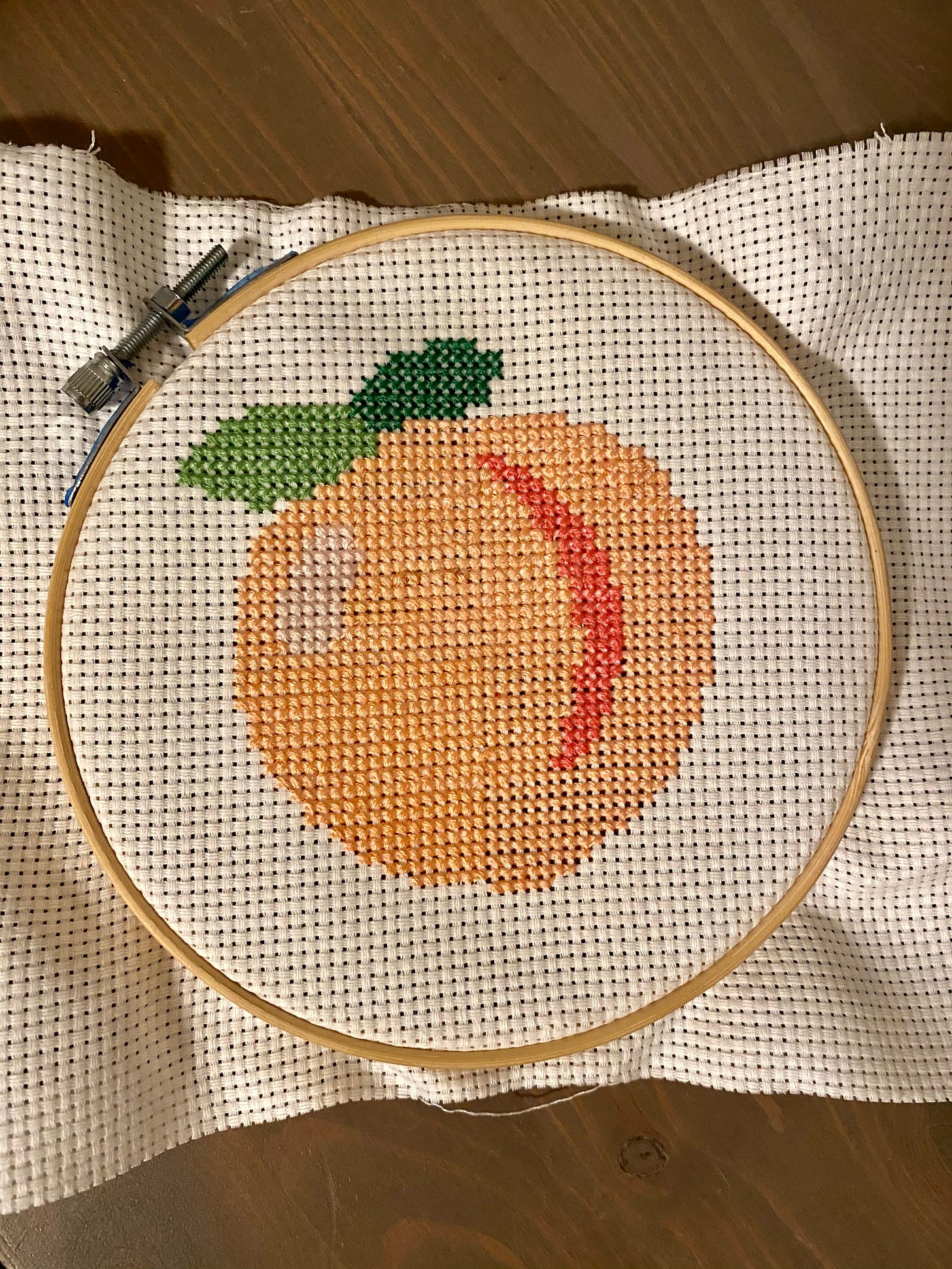 Cross-stitch of the peach emoji