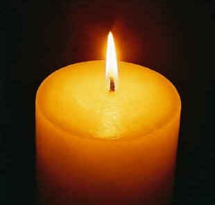 A lit yahrzeit candle (Jewish memorial candle) against a black background