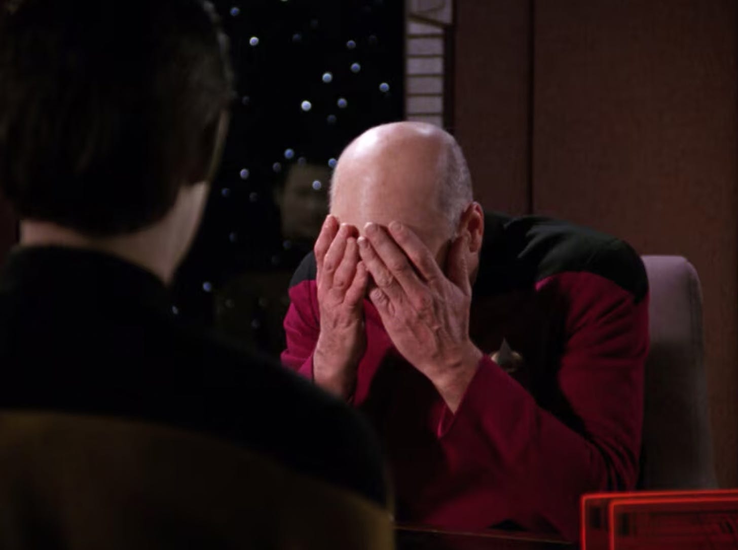 Captain Picard from Star Trek face-palming with both hands. He is wearing a red and black uniform.