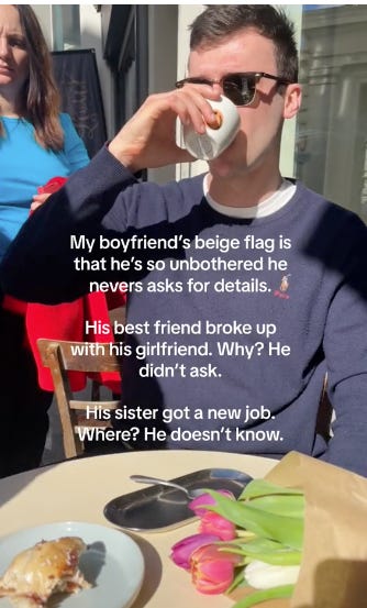 Short-haired brunette man in a navy sweater and wayfarer sunglasses sipping out of a white mug at a restaurant, overlaid text reads: “My boyfriend’s beige flag is that he’s so unbothered he never asks for details. His best friend broke up with his girlfriend. Why? He didn’t ask. His sister got a new job. Where? He doesn’t know”