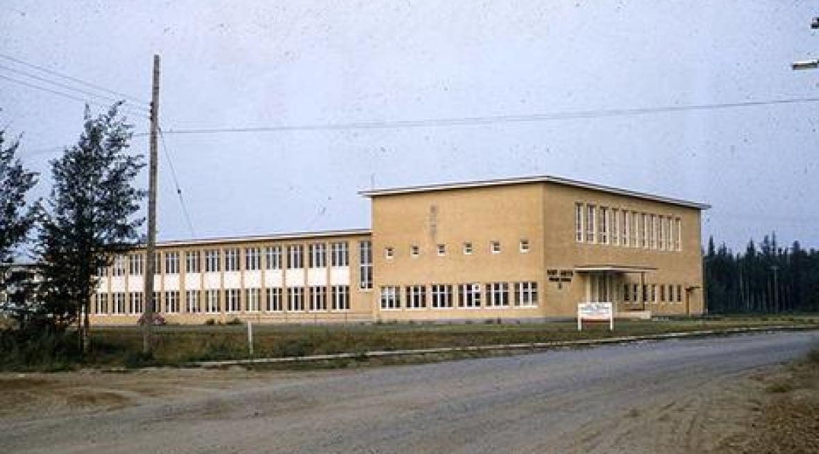 A beige school is seen from the road. A beige school is seen from the road.