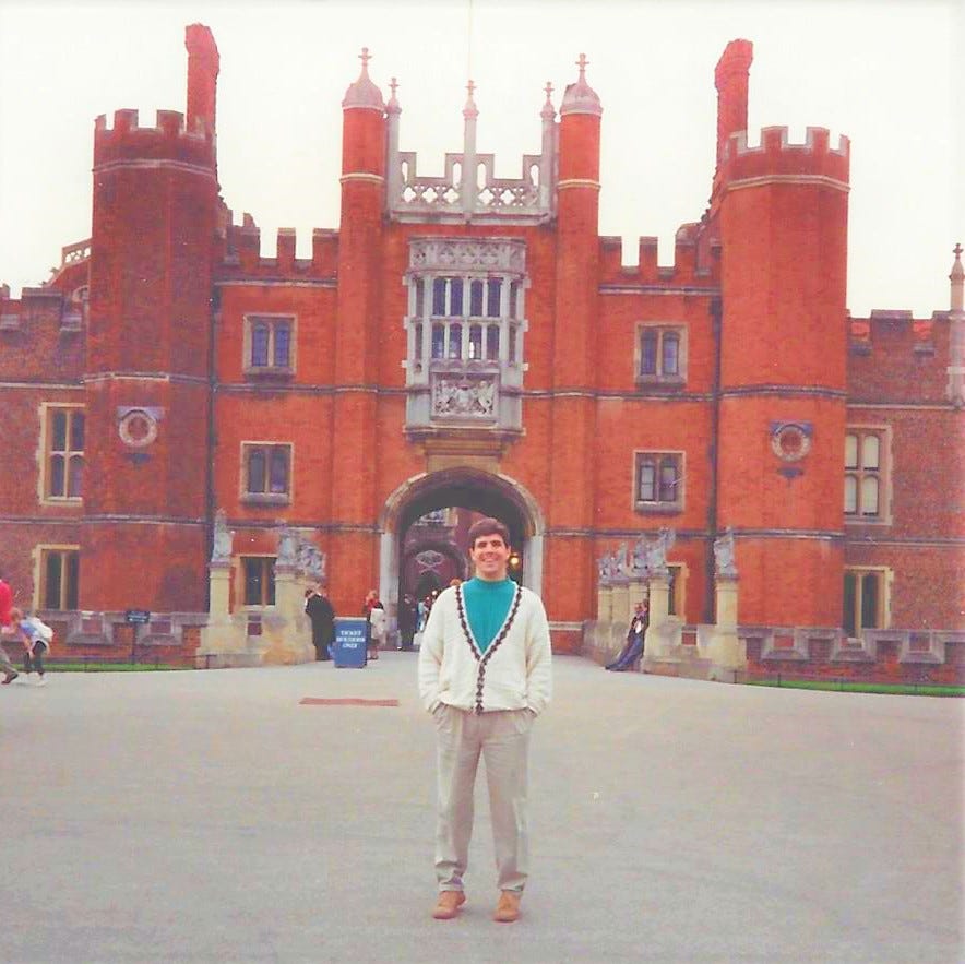 20-something man stand triumphantly in front of the real Hampton Court Palace