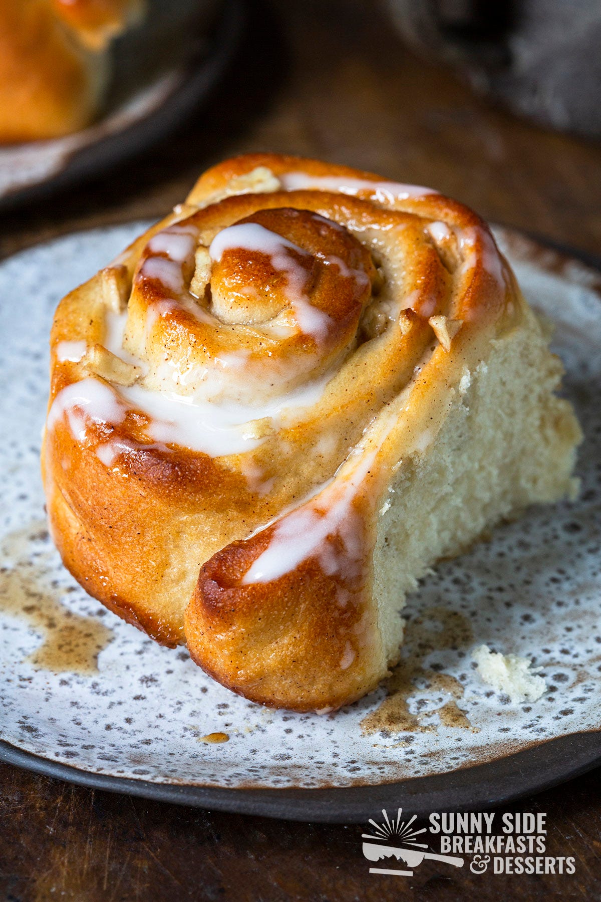 An apple pie cinnamon bun on a plate.