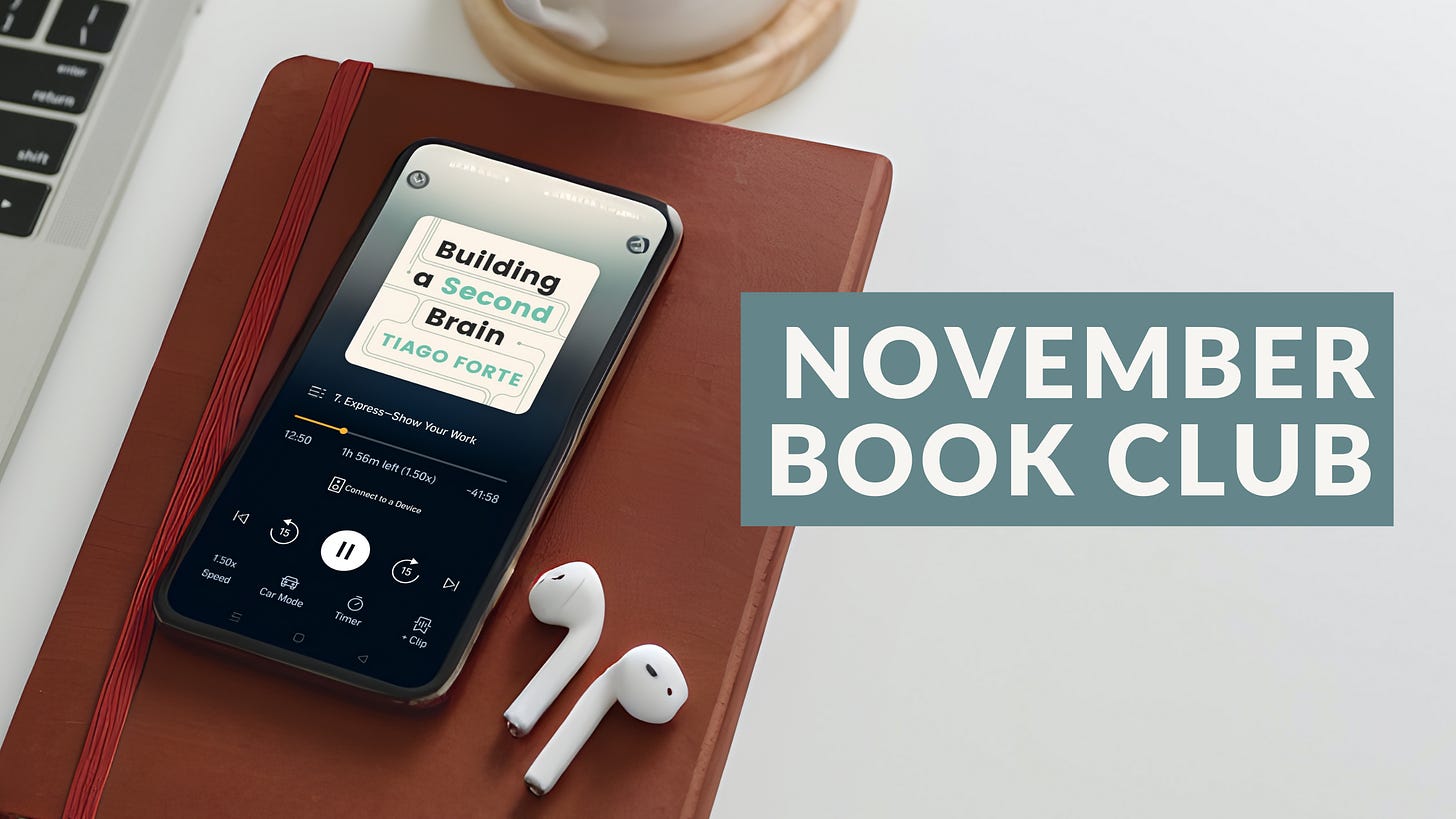 November Book Club: Building a Second Brain by Tiago Forte - img features a desk with earbuds and smartphone showing Audible version of the book