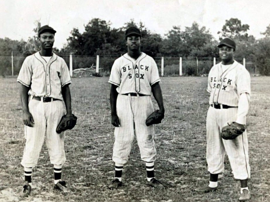 Three African American Baltimore Black Sox players, all dressed in uniform and wearing a baseball glove.