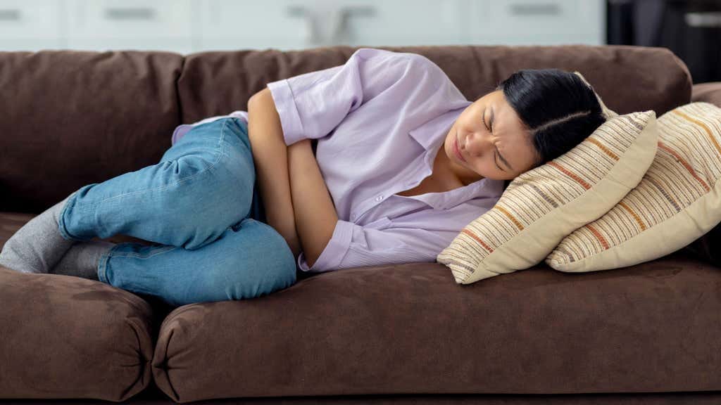 A young woman on the sofa with severe period pain