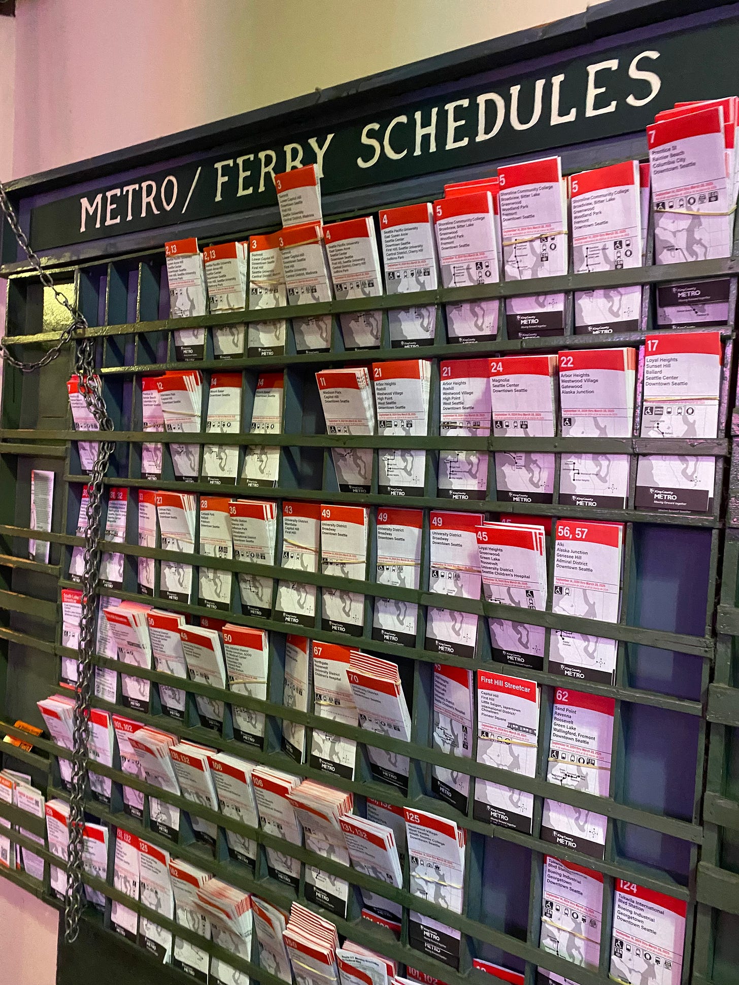 A wall of Metro and Ferry schedules, white pamphlets with red headers, and a few slots where there are no schedules. 