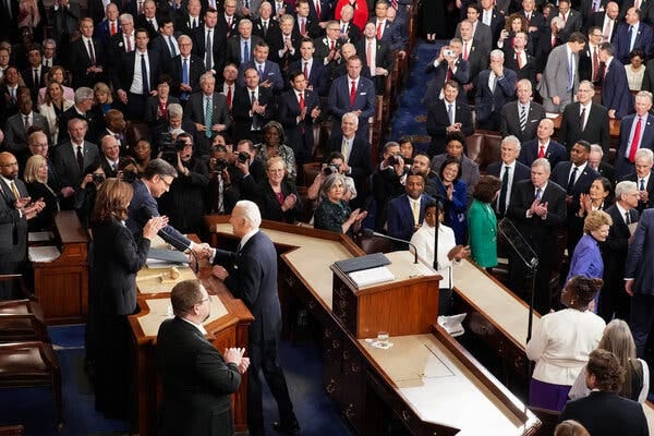 President Joe Biden shakes hands with Speaker Mike Johnson after handing him a copy of his State of the Union address on inside the House chamber.