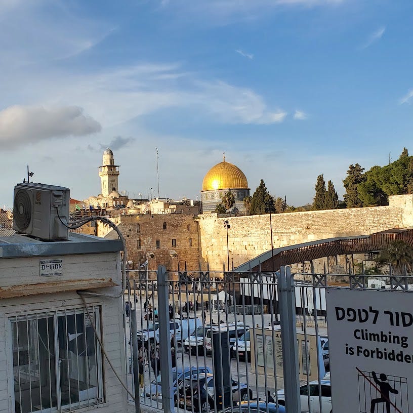 A gold dome looms over an ancient wall in Jerusalem. 