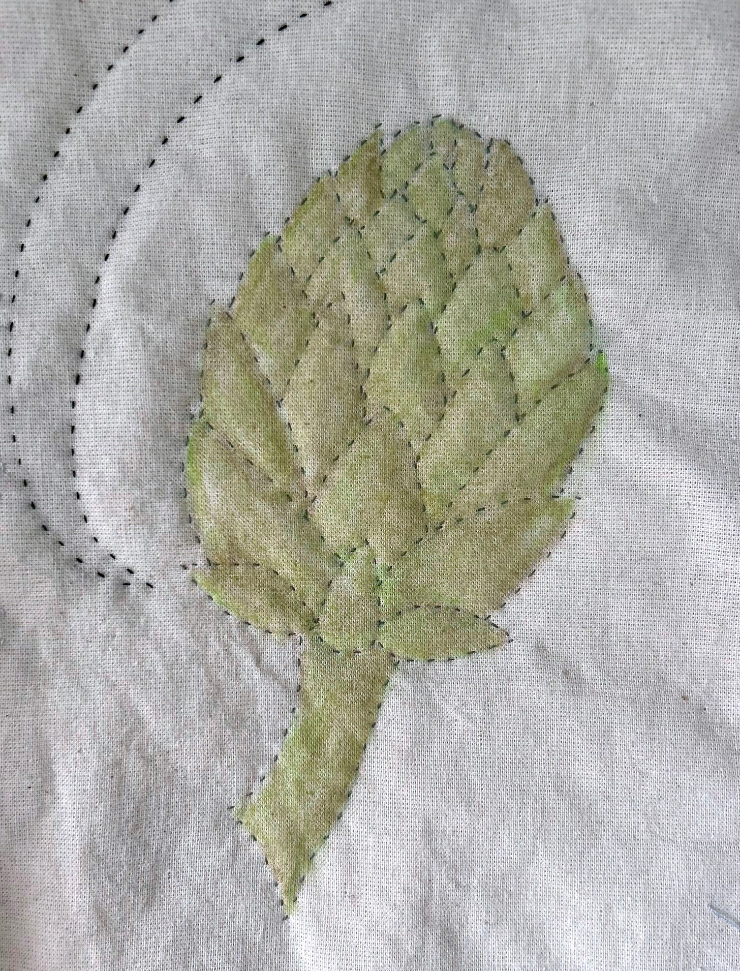 A stitched and coloured artichoke on cream calico. The artichoke is coloured in pale green.