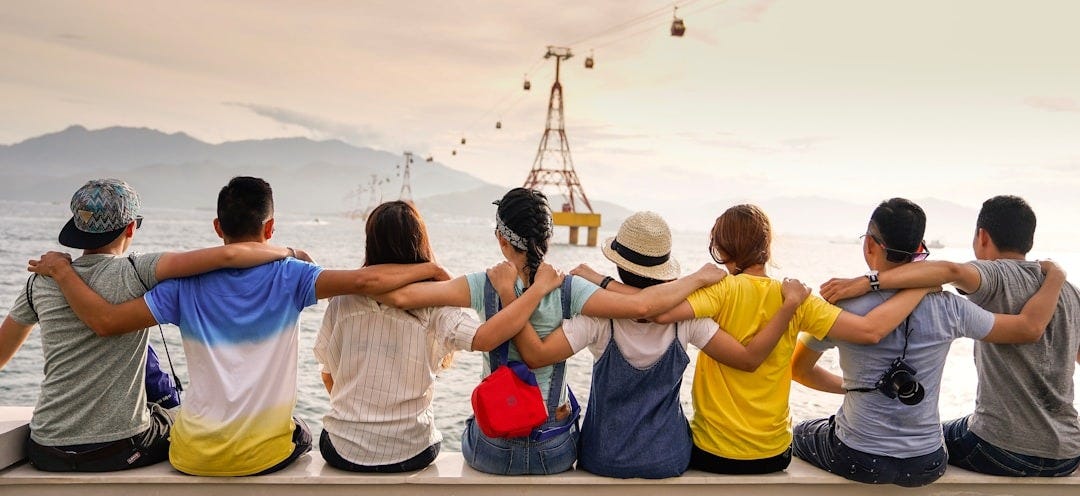 people holding shoulders sitting on wall