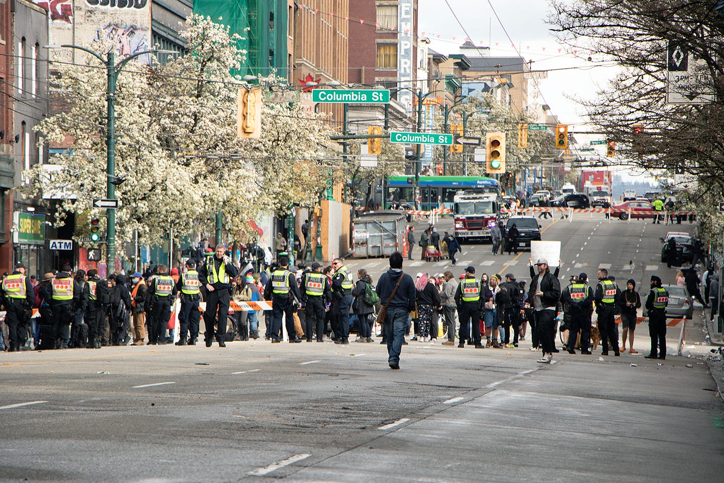 A photo from the end of the April 5 decampment and protest. A line of police are still seen holding back the protesters but the streets are already empty and the garbage trucks and city crews have already packed up and left.
