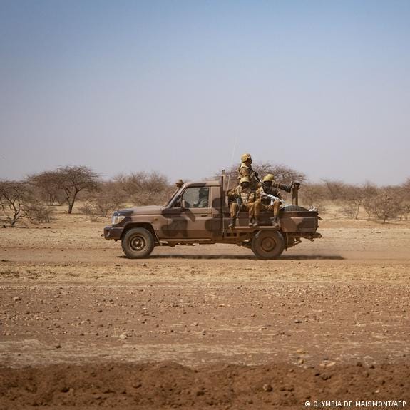 Burkina Faso soldiers patrol aboard a pick-up truck on a barren road 