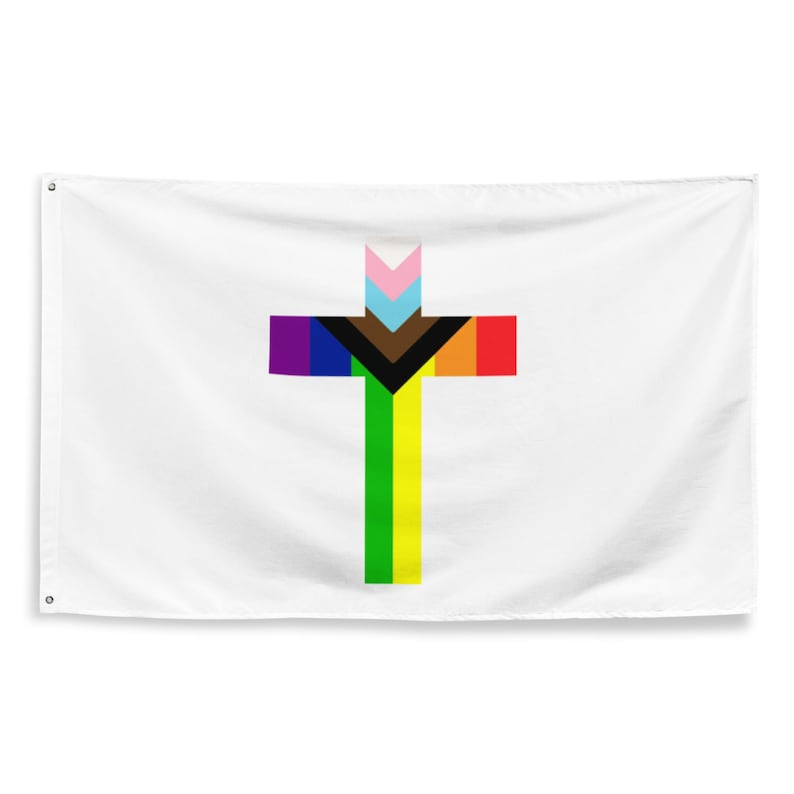 This is a white flag from Etsy (link to creator in bio) featuring a colorful cross in the middle -- the BIPOC, trans, and gay pride flags are super-imposed onto the cross.