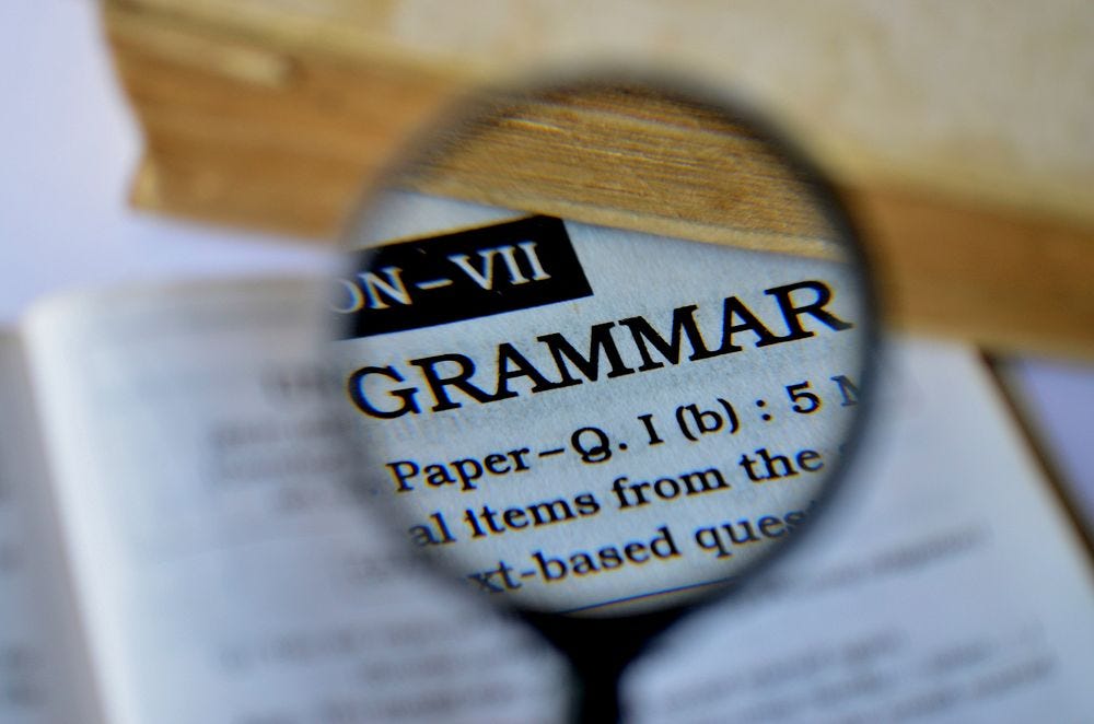 A magnifying glass over text, including the word "GRAMMAR"