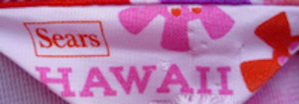 A brightly colored Sears Hawaii tag with red and pink letters and cartoon flowers.