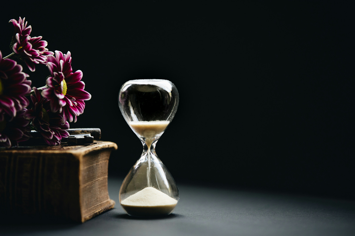 Hourglass with sand next to some flowers