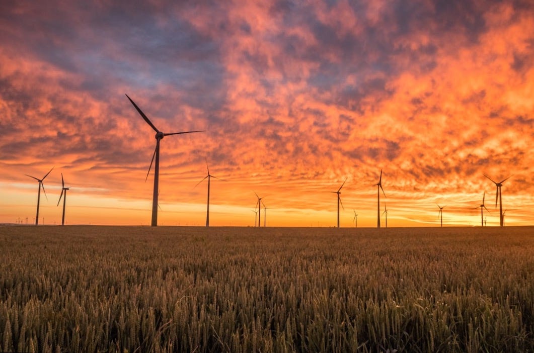 landscape photography of grass field with windmills under orange sunset