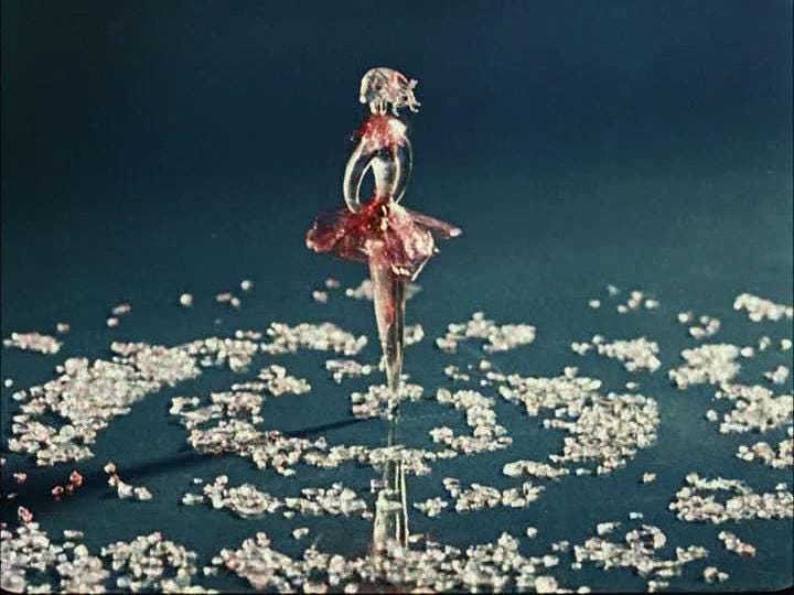 A still from 'Inspirace' (1949). A glass figurine of a ballerina stands in the centre of a spiral of glass shards.