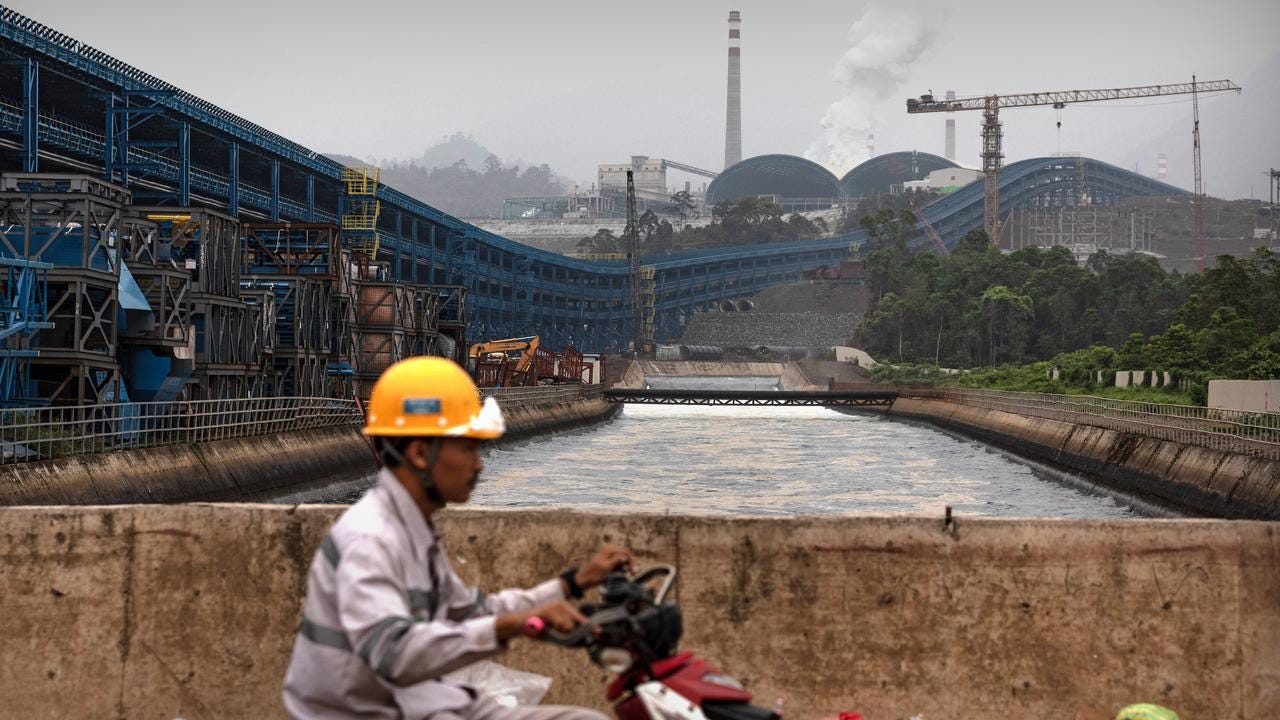 A worker passes the belching chimneys of Indonesia Morowali Industrial Park. Picture: Garry Lotulung.