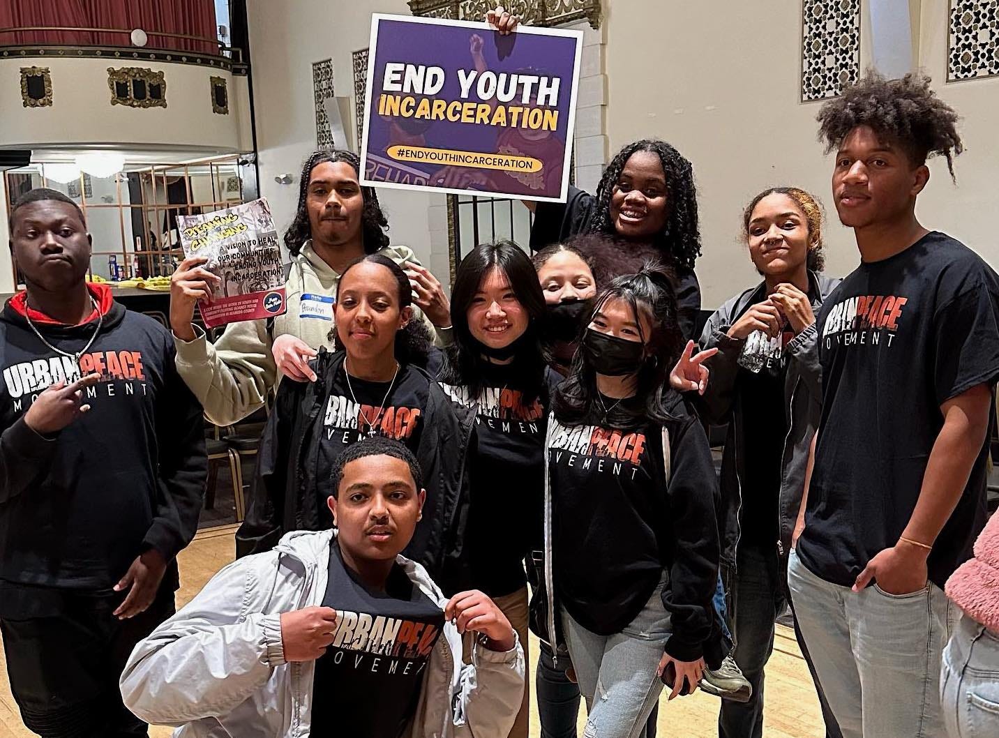 a group of young people in UPM t-shirts holding a sign "End Youth Incarceration"