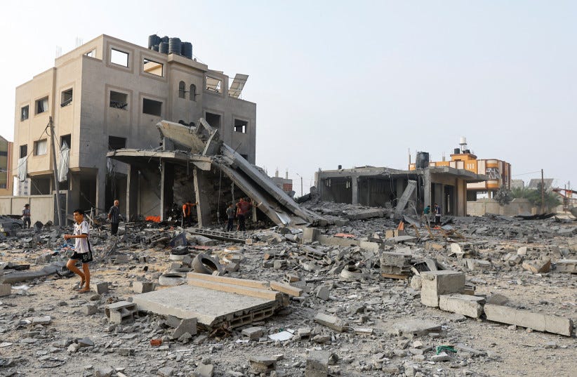  Palestinians inspect the site of Israeli strikes on a house in Khan Younis in the southern Gaza Strip, October 23, 2023 (photo credit: REUTERS/IBRAHEEM ABU MUSTAFA)