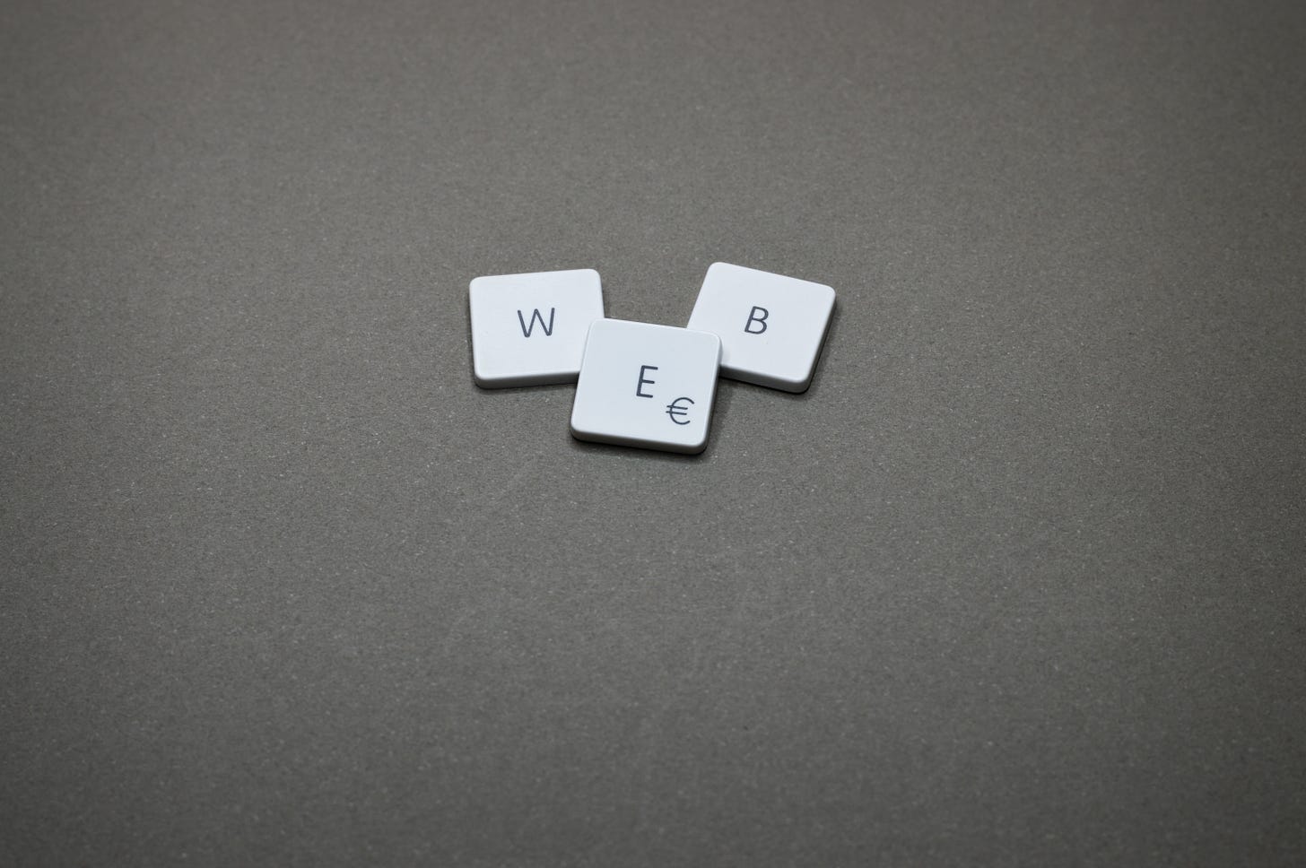 WEB spelled in scrabble pieces on a gray background