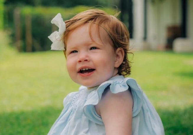 Princess Lilibet in a blue dress smiling 