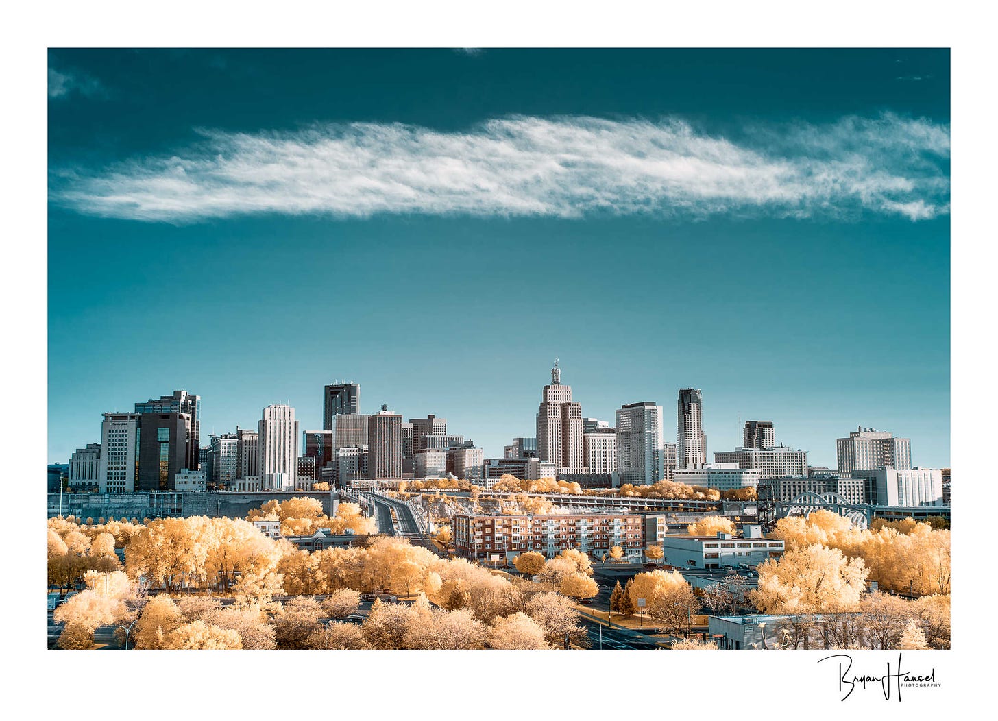 The skyline of St. Paul with a blue sky and yellow trees.