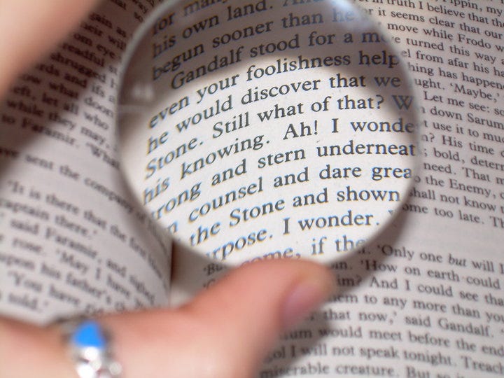 A hand holds a lens over the text of Lord of the Rings
