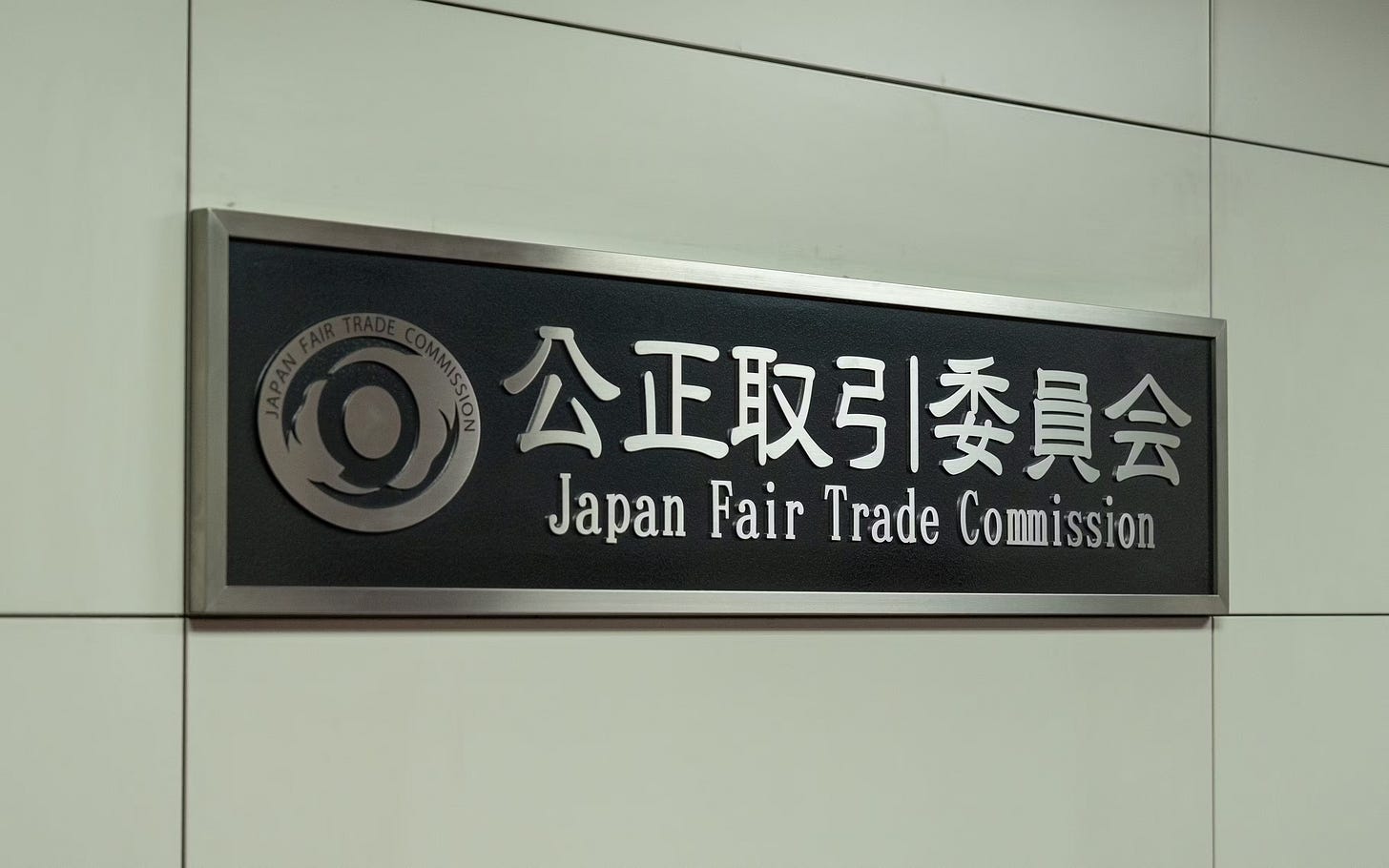 Wall plaque displays the logo and names of the Japan Fair Trade Commission in Japanese and English.