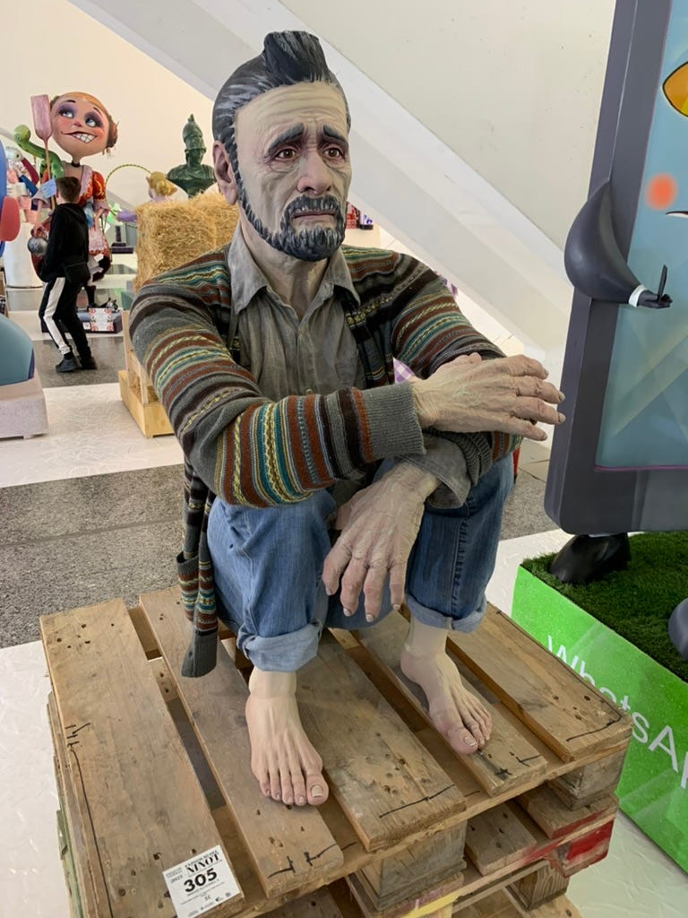 A realistic man with incredibly sad eyes crouches on a pallet