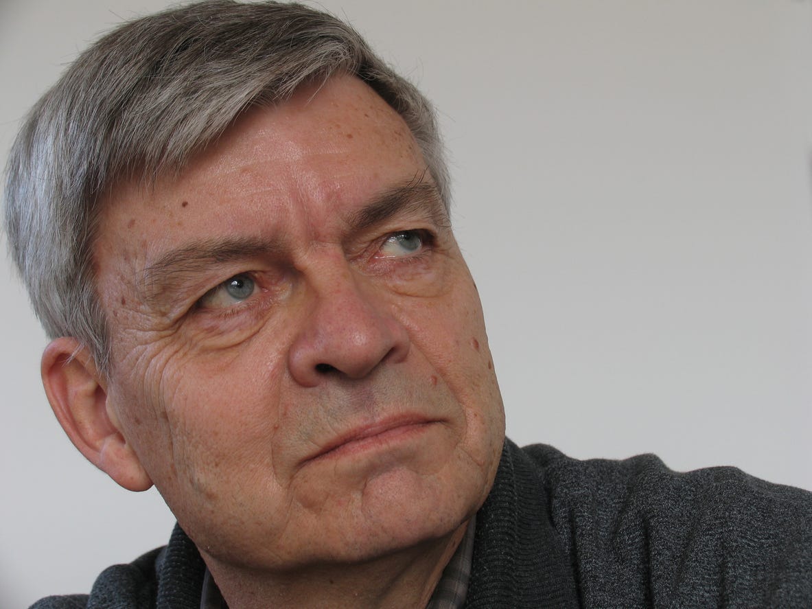 Discerning, older white man with full head of graying hair looking off to the right with his head tilted to left. 