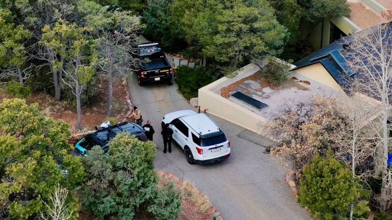 Law enforcement officials talk Thursday outside the home of actor Gene Hackman in Santa Fe, New Mexico. - Roberto Rosales/AP