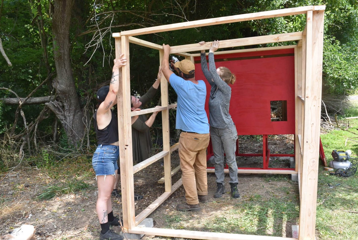 Four people framing a chicken coop