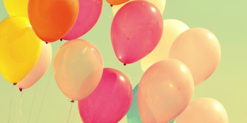 group of pink, orange and yellow balloons against green background