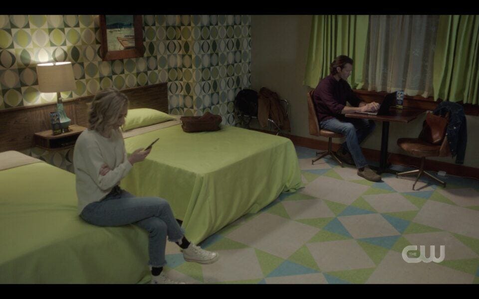 Sam Winchester researcing in motel room with Caitlin on Bed SUpernatural