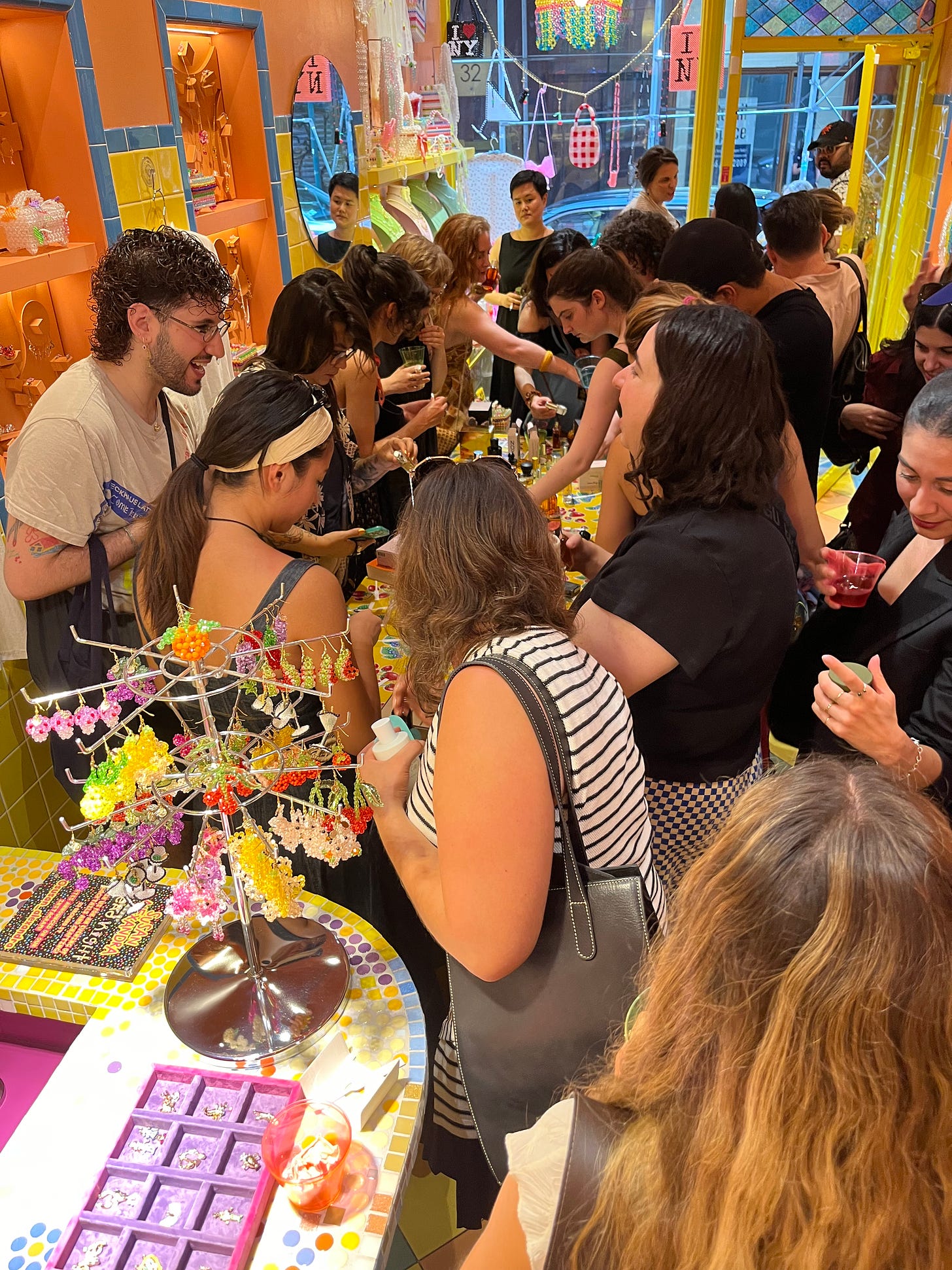 a large group of people surrounding a table of perfume bottles