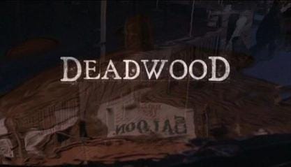 This image shows the title card of David Milch's HBO series Deadwood (2004-2006). The word "Deadwood" lies in the center of a shot of the town's main saloon and thoroughfare as reflected in a rain puddle.