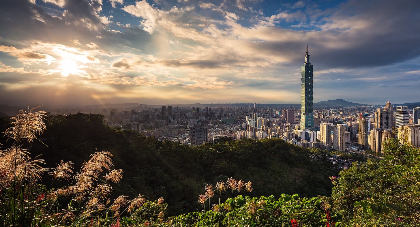 Fotografia panorâmica em cores de Taipei em dia de sol, com destaque para a torre Taipei 101.