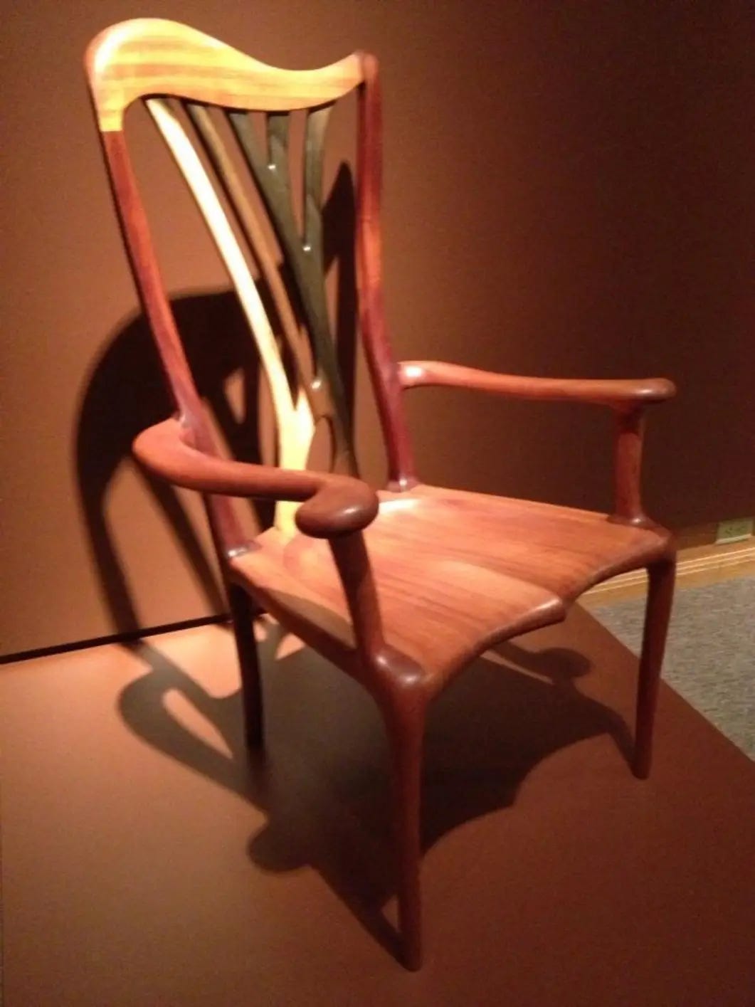 a complicated arm chair with swirling lines and multiple colors of wood