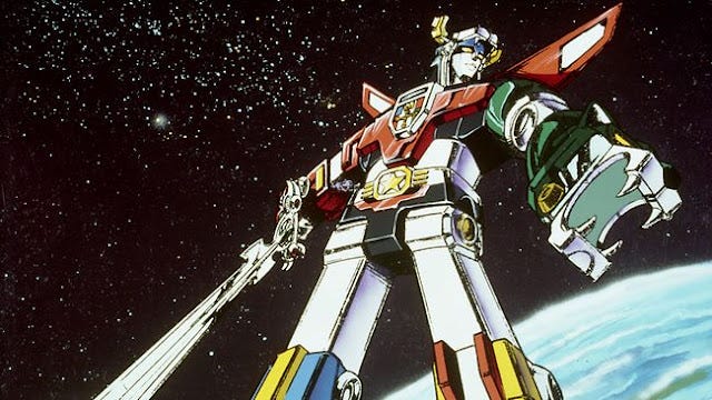 A still image of Voltron, a cartoon construct created by combining 5 lion machines. It has different colored lions for feet and hands, and its face is adorned wth a black lion. Voltron is holding a sword off to the side, and is hovering in outer space. A still image of Voltron, a cartoon construct created by combining 5 lion machines. It has different colored lions for feet and hands, and its face is adorned wth a black lion. Voltron is holding a sword off to the side, and is hovering in outer space.